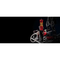 Simagic Pedais P2000 Crimson Edition, vista lateral: cilindro hidráulico vermelho com mola dourada e mangueira trançada em