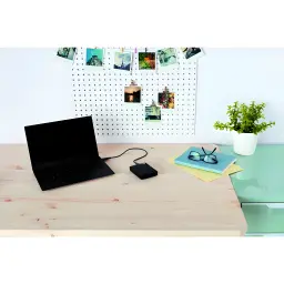 WD Elements Portable 2TB noir, scène bureau: branché par câble à un laptop sur bureau en bois avec photos polaroid sur