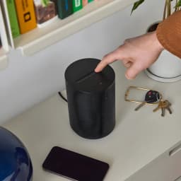 Sonos Era 100 SL noir, usage: main sur panneau tactile supérieur posé sur bureau avec clés et smartphone