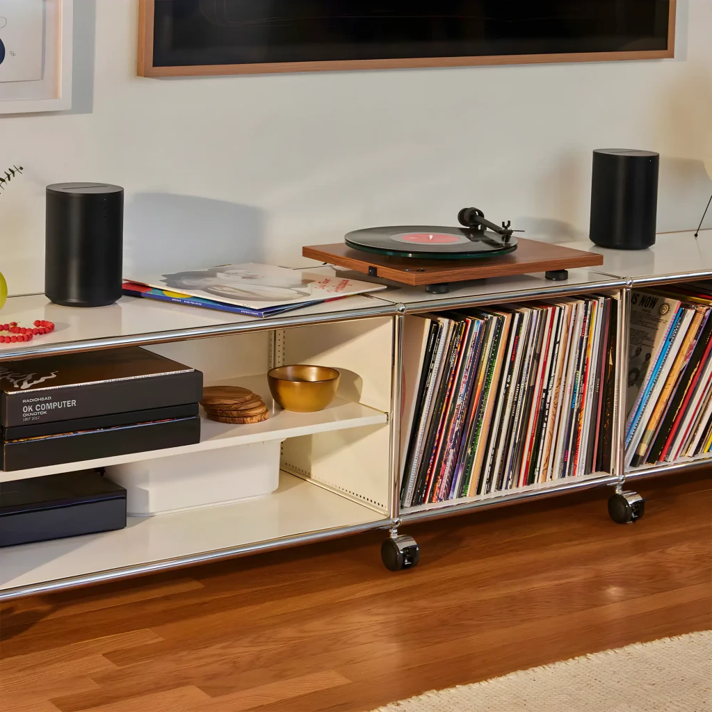 Sonos Era 100 SL noir, vue lifestyle: deux enceintes sur meuble avec platine vinyle et collection de disques