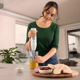 Braun Minipimer MultiQuick 5 MQ 50001 M branco, uso: mulher triturando molho em copo medidor em cozinha moderna