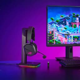 ASUS ROG Pelta noir, sur support: casque avec logo ROG éclairé, micro et hub RGB sur bureau gaming avec écran