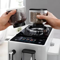 De'Longhi Rivelia EXAM440.35B Branco, detalhe: mãos inserindo dois reservatórios de grãos no moedor cônico superior