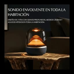 Harman Kardon Aura Studio 5 negro, vista frontal en ambiente: cúpula transparente con luz ámbar sobre mesa de mármol oscuro