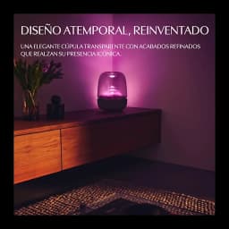 Harman Kardon Aura Studio 5 negro, ambiente: cúpula transparente iluminada en rosa sobre mueble de madera en salón oscuro