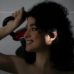 Nilox NXTWRUNBEATOR Bluetooth negro, uso deportivo: mujer con auricular en oreja sujetando kettlebell roja