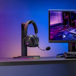 ASUS ROG Delta II Negro, vista lifestyle: auriculares en soporte RGB sobre escritorio gaming con monitor y retroiluminación