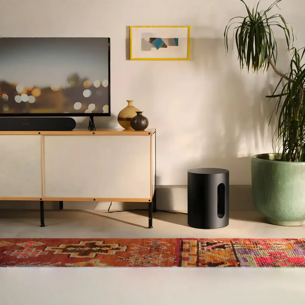 Sonos Sub Mini noir, vue en perspective: corps cylindrique mat avec fente de port bass reflex central et logo sur le dessus - Ítem3