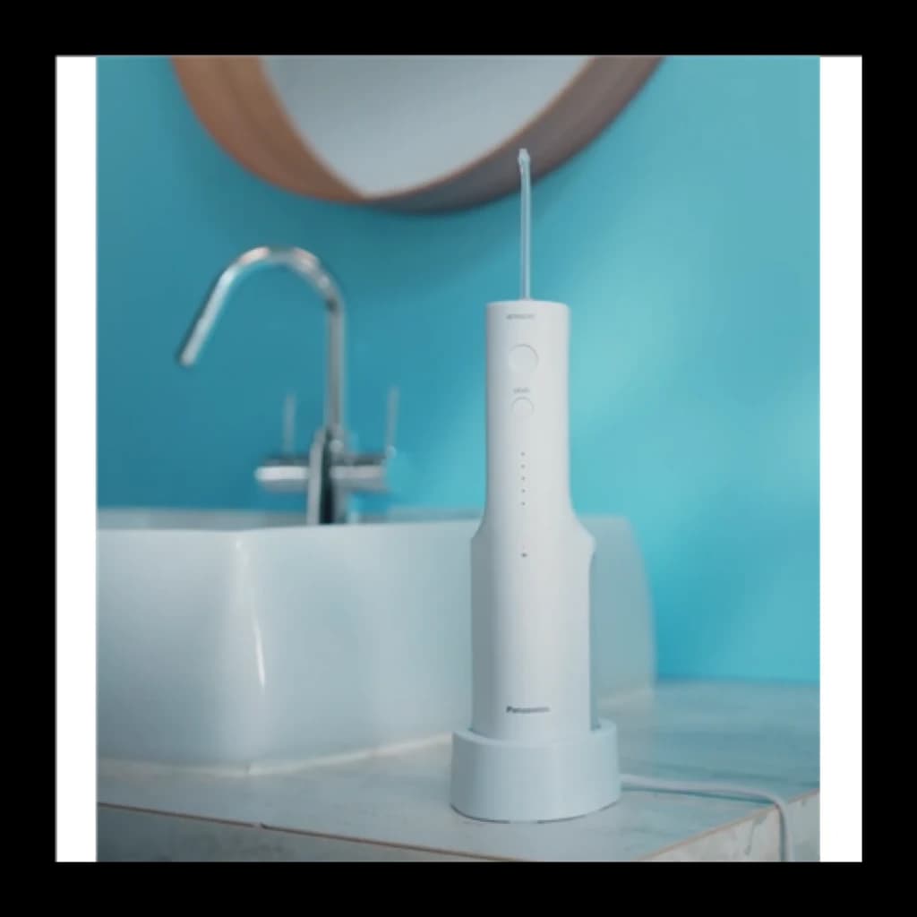 Panasonic irrigateur buccal EW-DJ26 violet, vue lifestyle: appareil sur socle posé sur plan de salle de bain avec robinet et