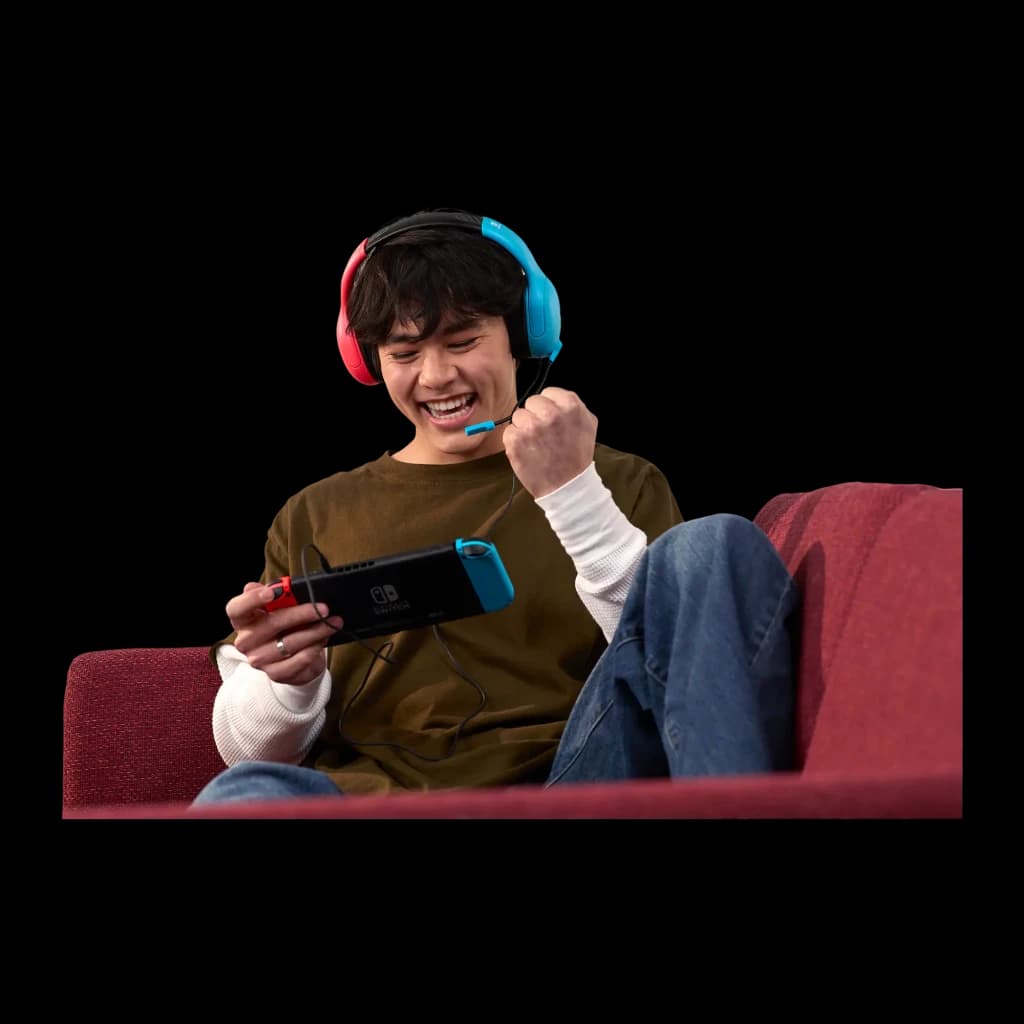 Turtle Beach Airlite Fit Neon Blue & Red azul, uso: chico sonriente en sofá jugando con Nintendo Switch conectada a los