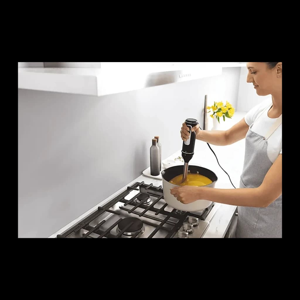 Ninja Foodi CI100EU Mixeur plongeant noir, utilisation: femme mixant une soupe jaune dans une casserole sur gazinière