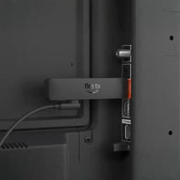 Leitor Multimédia Amazon Fire TV Stick HD 2026 conectado à porta HDMI da TV, dongle compacto com WiFi 6 e cabo USB, design preto com logotipo fire tv