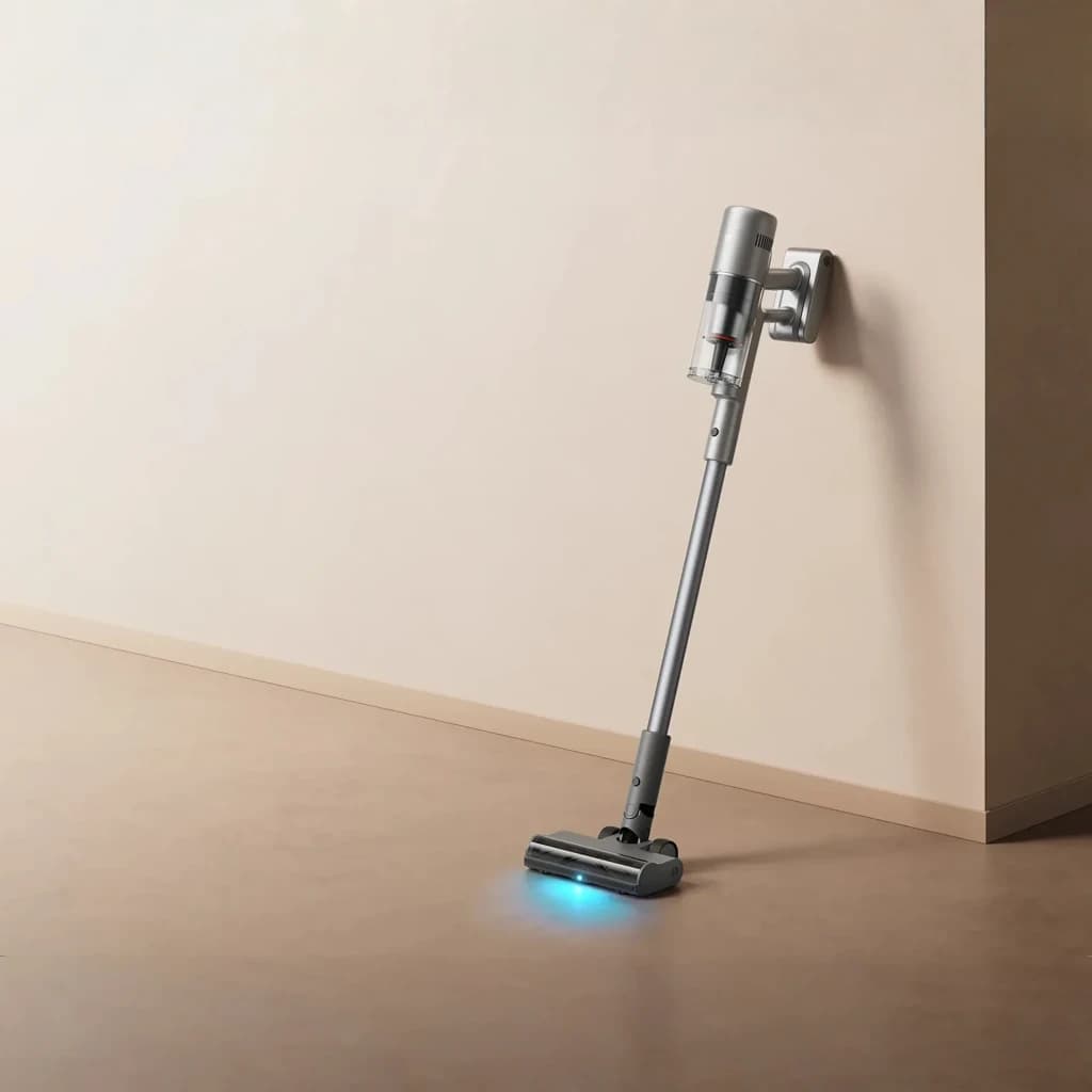 Aspiradora vertical sin cable gris con base mural, tubo largo y cepillo motorizado con luz LED azul; diseño minimalista y depósito transparente visible