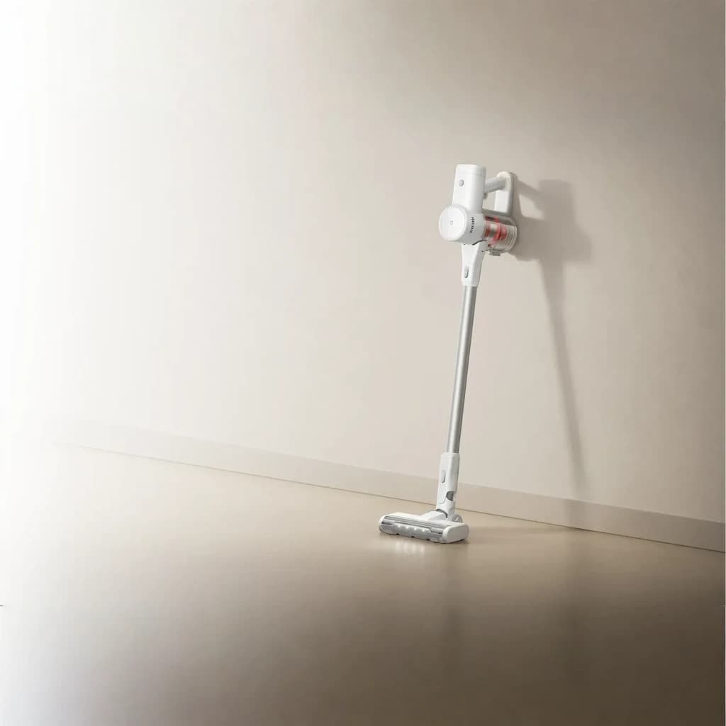 Aspiradora escoba inalámbrica blanca con base de pared, tubo largo y cabezal motorizado de rodillo; diseño minimalista y compacto, depósito transparente con