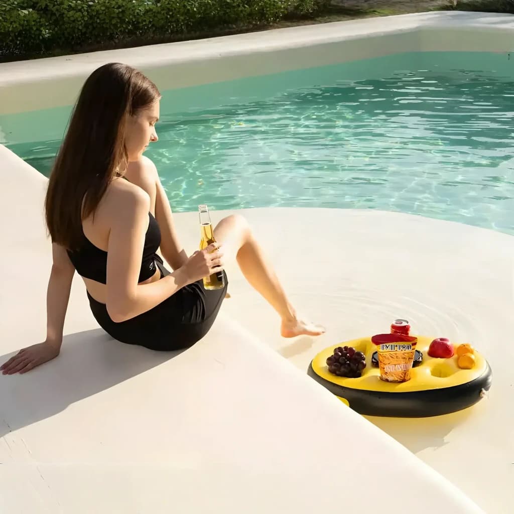Bandeja flutuante amarela circular com porta-copos e compartimentos, boiando na piscina com bebidas e frutas; ideal para uso à beira da água
