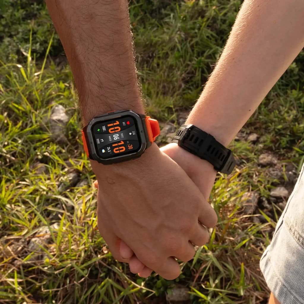 Reloj robusto negro con bisel metálico, correa naranja, pantalla cuadrada a color, métricas FC y SpO2 visibles, diseño outdoor resistente y deportivo