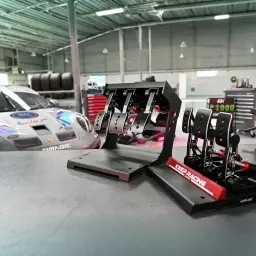 Simagic P1000 Modular Invertido 3 Pedais Preto, vista lateral: pedais invertidos pretos com detalhes vermelhos em garagem de