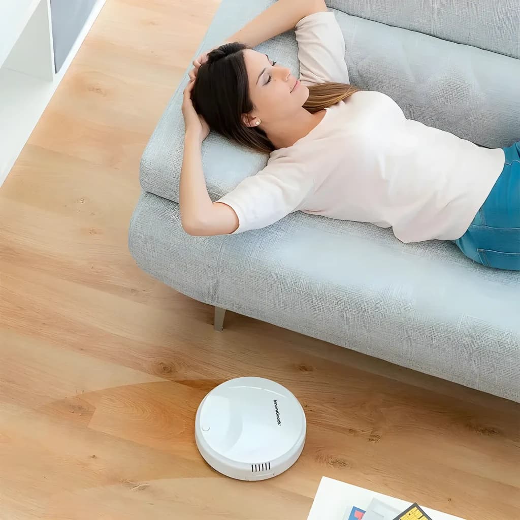 Roborock Saros Z70 blanco, vista lifestyle: robot aspirador limpiando suelo de madera mientras mujer descansa en sofá