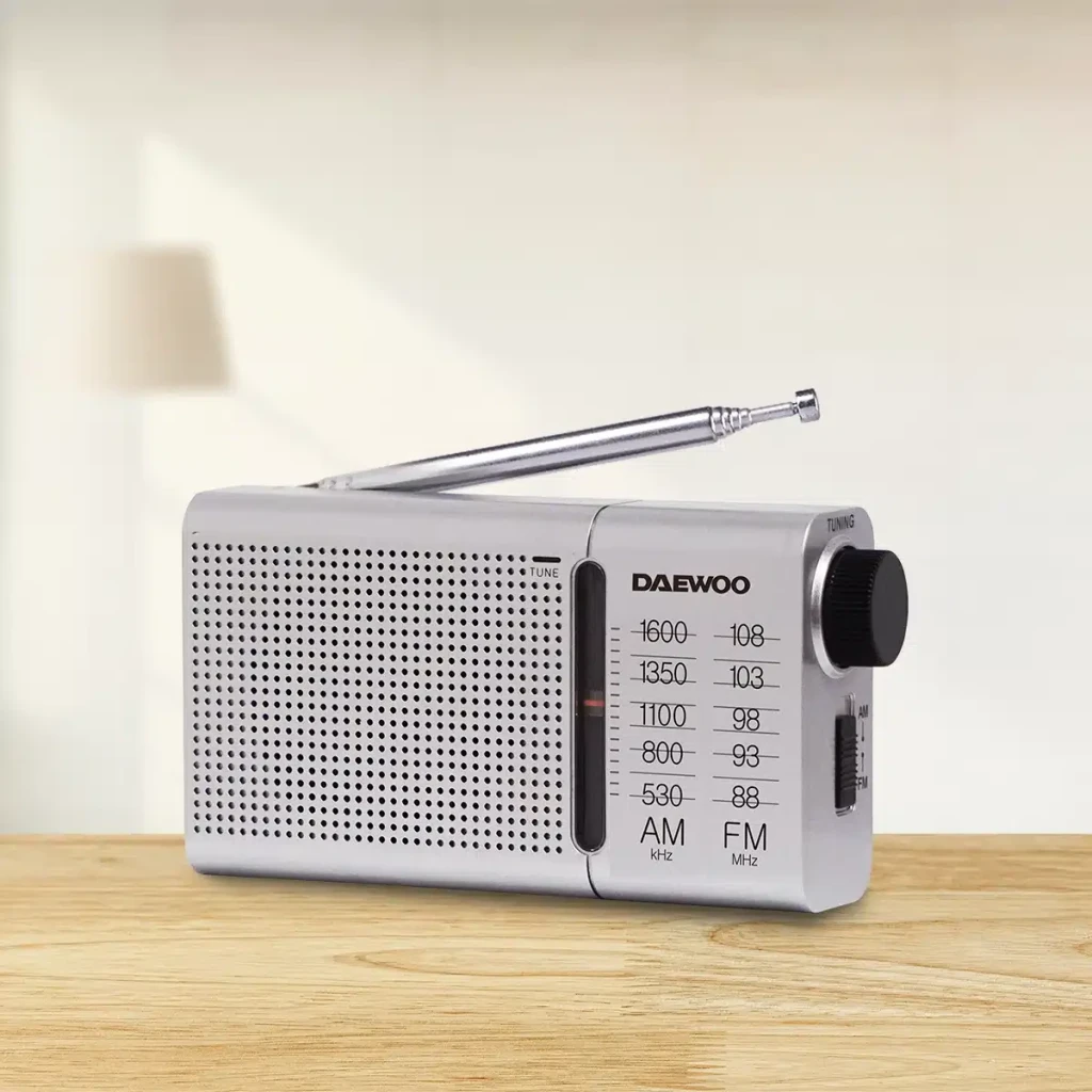 Radio portable Daewoo AM/FM Piles AA Argent DW1037, en utilisation: vue latérale sur table en bois avec antenne déployée