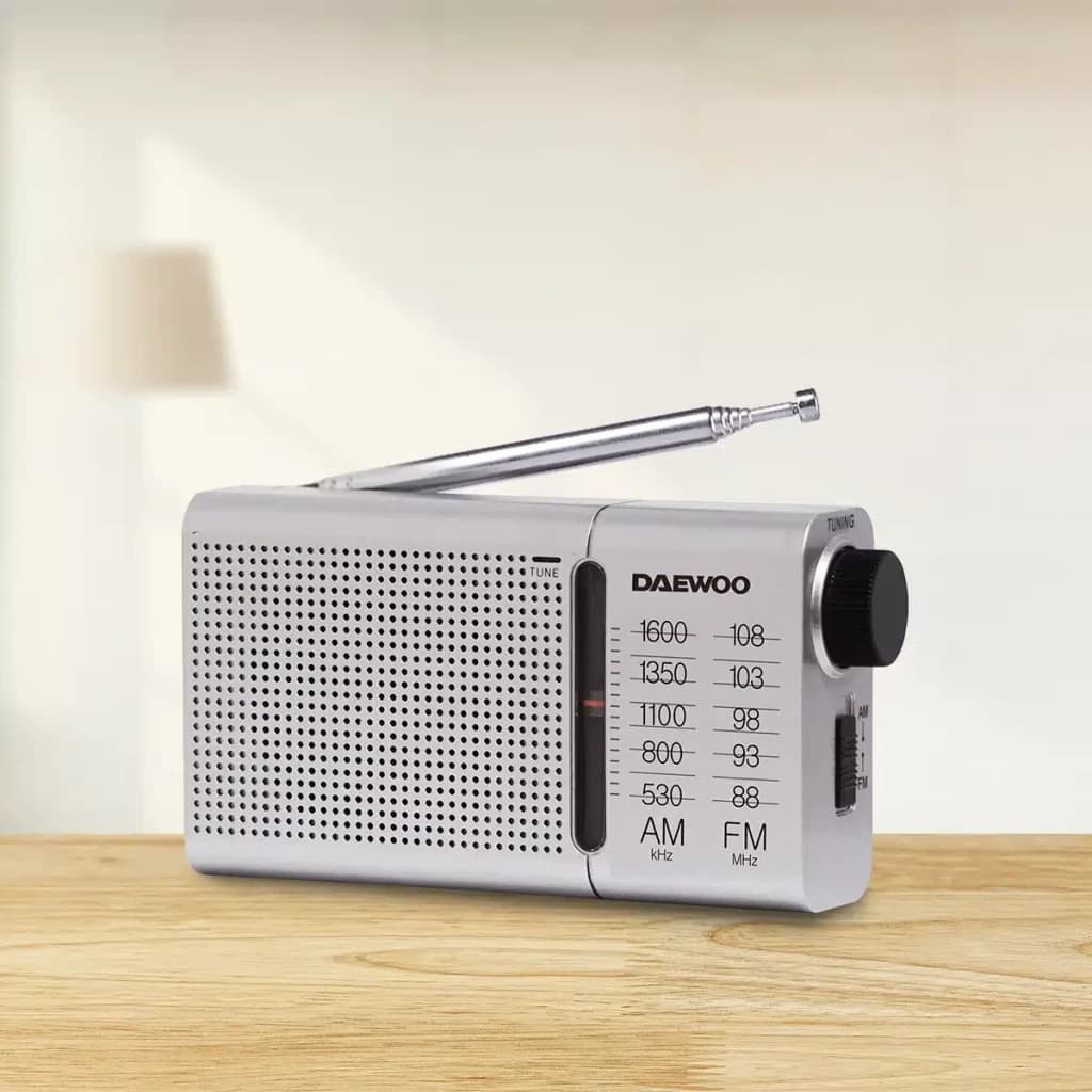 Radio portable Daewoo AM/FM Piles AA Argent DW1037, en utilisation: vue latérale sur table en bois avec antenne déployée