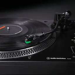 Audio-Technica AT-LP120X noir, détail: cellule avec diamant vert posé sur disque vinyle en rotation