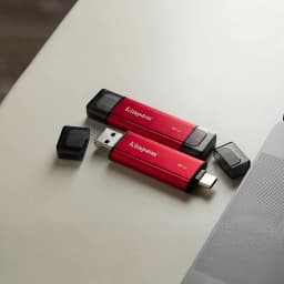 Kingston SPSD 1TB Preto Vermelho, vista lifestyle: duas unidades sobre mesa mostrando conectores USB-A e USB-C descobertos