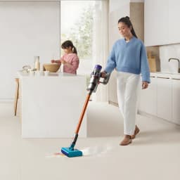 Aspirateur Dyson Cyclone V10 Submarine sans fil, tube orange, tête bleue pour sec et humide, nettoie des éclaboussures au sol dans une cuisine lumineuse