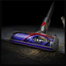 Brosse motorisée du Dyson Cyclone V10 Submarine aspirant poussière et débris sur sol dur et tapis, coupe transversale montrant flux d’air et rouleau