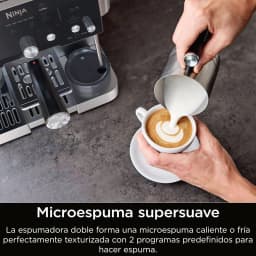 Ninja Luxe Cafe Essential ES501EU cafeteira castanha, uso: mãos vertendo microespuma em xícara com latte art ao lado