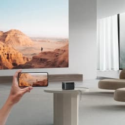 Dangbei Mars Pro 2 Laser 4K UHD preto 32GB, uso em sala: projeta paisagem na parede, mão segura telemóvel com mesma cena