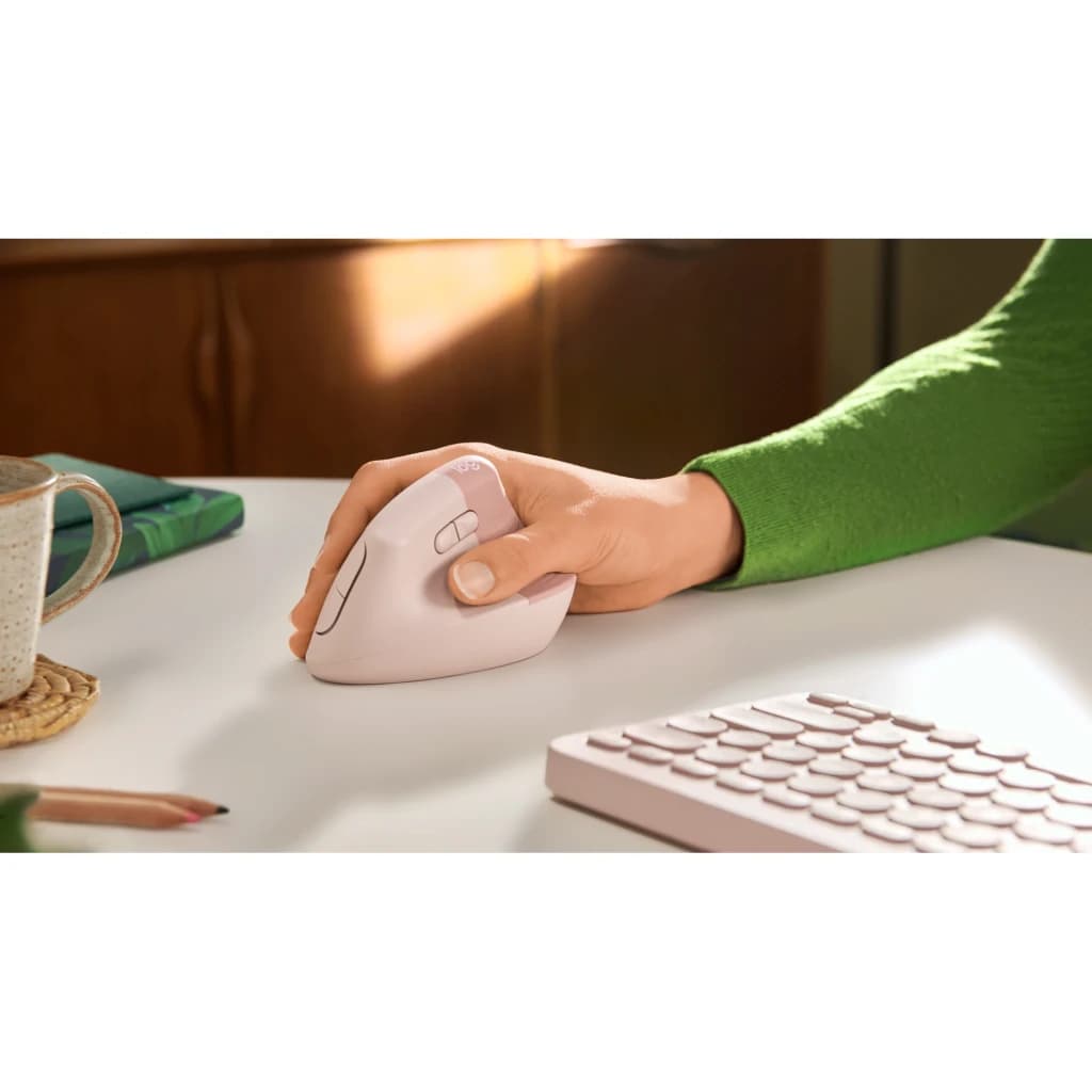 Logitech Ratón Lift Vertical Ergonómico Rosa, uso: mano sujetando el ratón en escritorio con teclado rosa al fondo