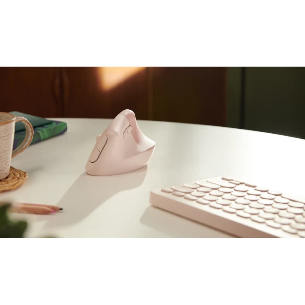 Logitech Ratón Lift Vertical Ergonómico Rosa, vista lifestyle: ratón sobre escritorio blanco junto a teclado y taza