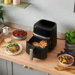 Russell Hobbs SatisFry 4.3L noir, vue lifestyle: tiroir ouvert avec aliments cuits sur plan de travail de cuisine