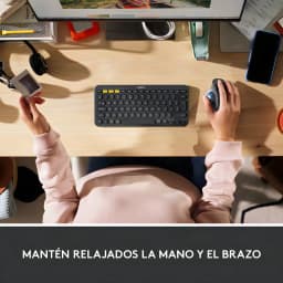 Logitech Ratón ERGO M575S Grafito, vista cenital: mano sujetando el ratón trackball en escritorio junto a teclado Logitech