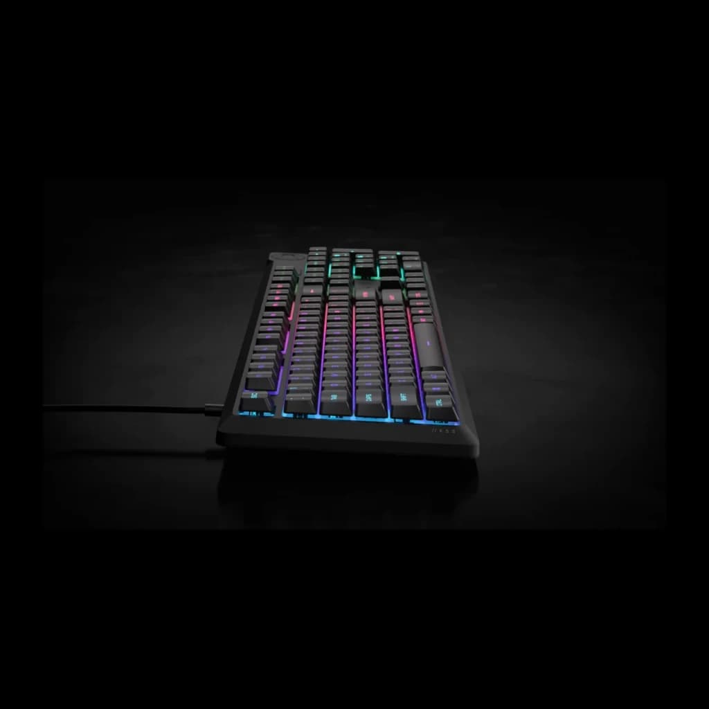Corsair Clavier K55 Core noir, vue latérale en angle bas: rétroéclairage RGB mis en valeur dans un environnement sombre