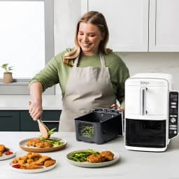 Ninja Double Stack XL SL400EUWH blanco, uso en cocina: mujer sirve comida junto a la freidora con cesta extraída y platos
