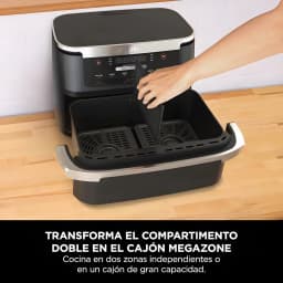Ninja AF550EU freidora aire 6.6L negra, cajón abierto: mano retirando divisor para convertir doble zona en MegaZone