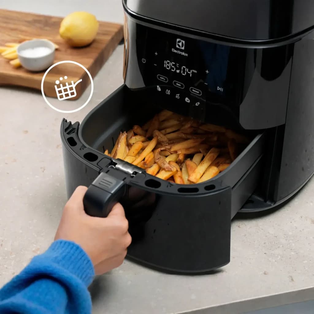 Electrolux Fritadeira ar EAF7B 6,8L preto, gaveta aberta: mão retirando cesto com batatas fritas e painel digital visível