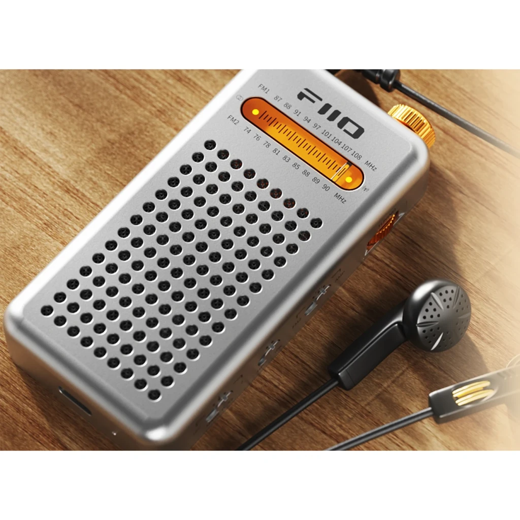 FiiO RR13 Plata, vista superior en madera: rejilla frontal, dial FM iluminado en naranja y auriculares conectados