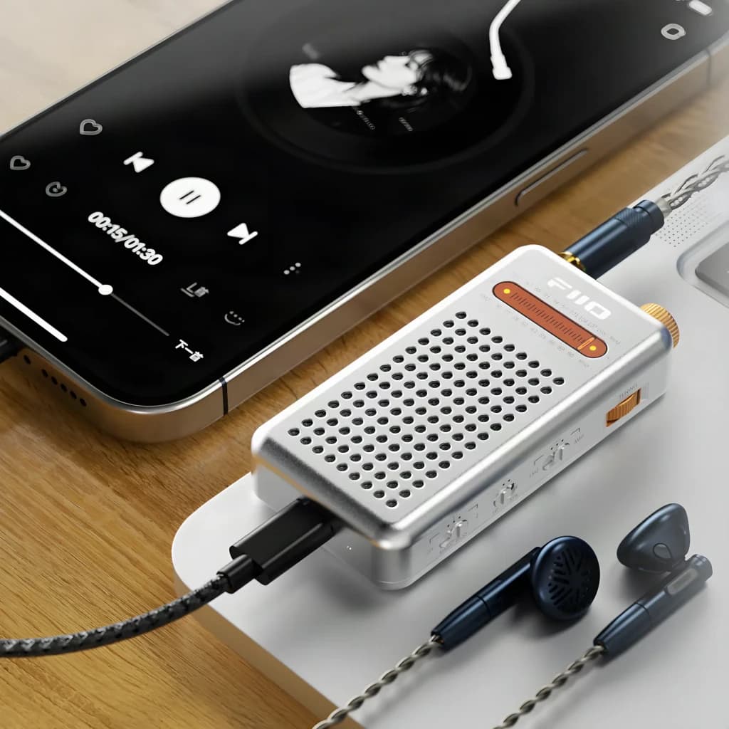 FiiO RR13 Plata, vista en uso: conectado a smartphone con auriculares IEM sobre superficie de madera