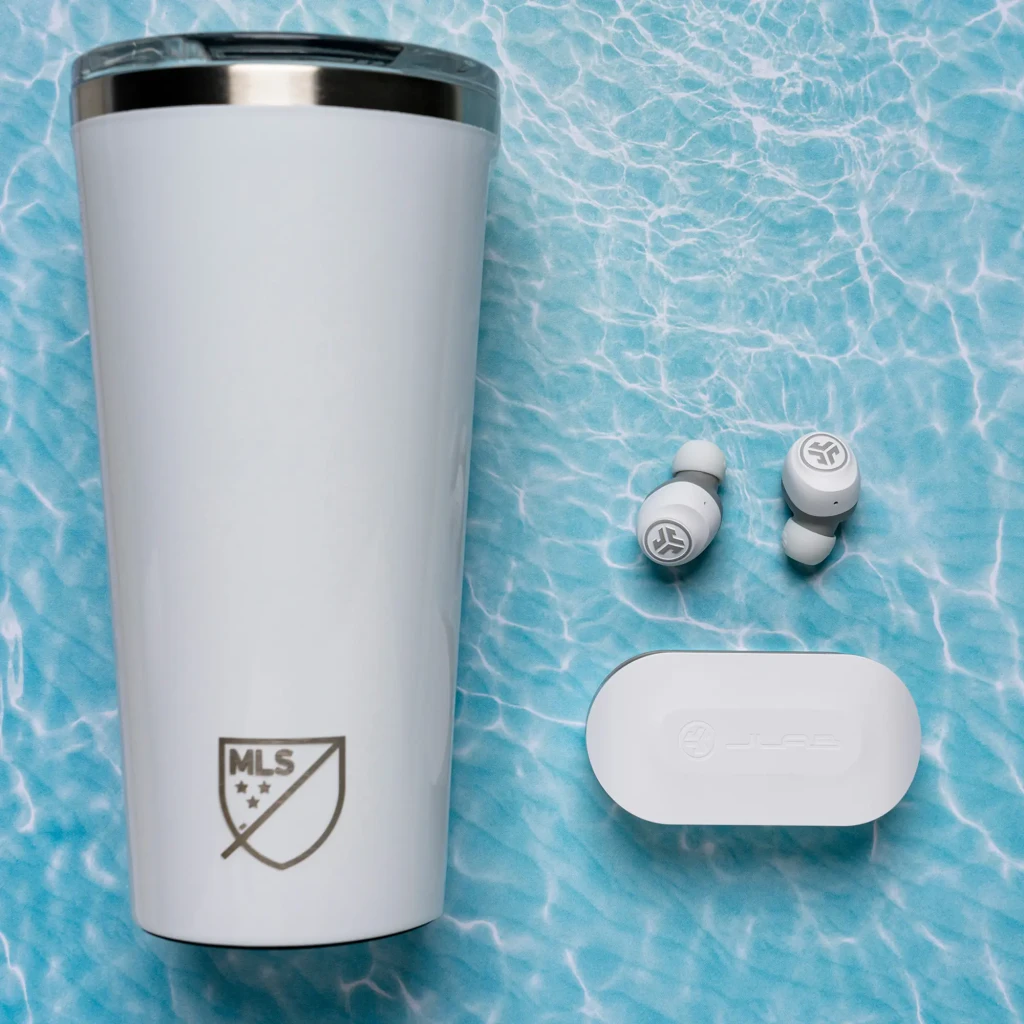 Auriculares JLab Audio GO Air TWS Bluetooth 5.0 20h Blanco, lifestyle: earbuds y estuche blancos junto a vaso MLS