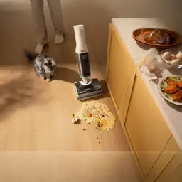 Roborock F25 RT 2,5Ah blanco, uso en cocina: limpia derrame de huevo en suelo de madera con gato al lado