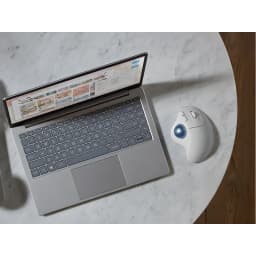 Logitech Trackball Ergo M575s Blanco, vista cenital: trackball junto a portátil sobre mesa de mármol