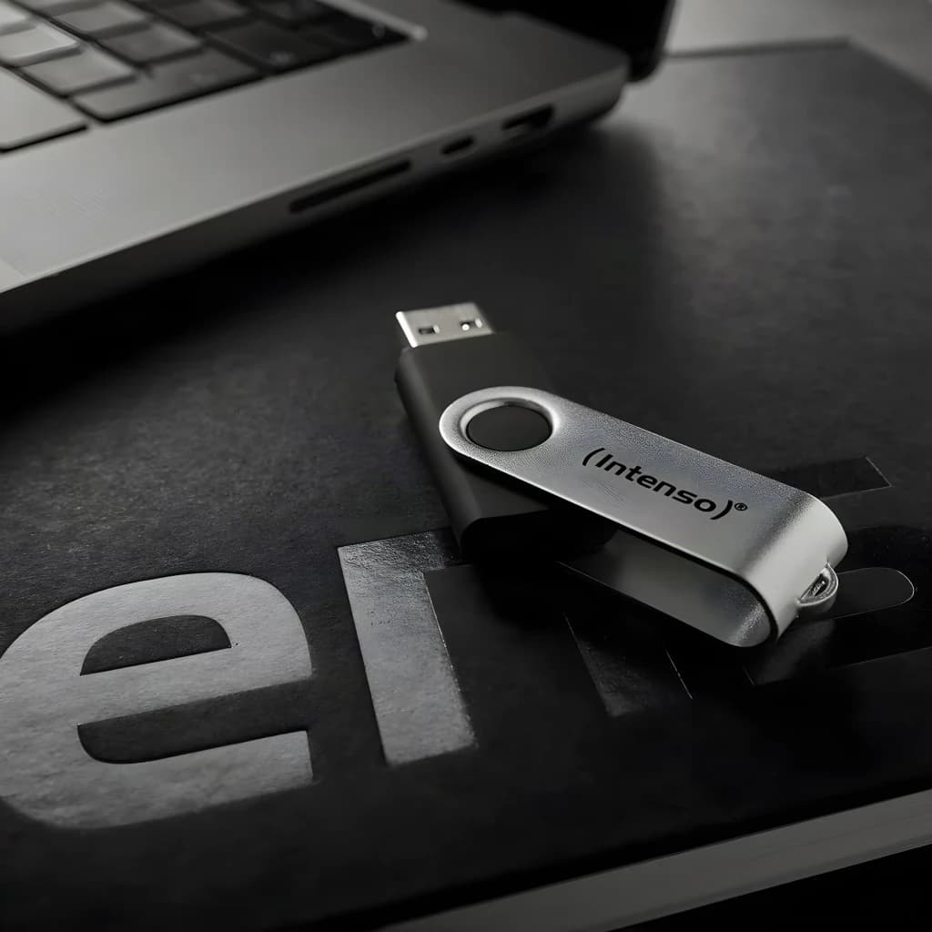 Intenso Office Line 256GB preto, vista lifestyle: pen drive com corpo preto e clip prateado sobre secretária junto a portátil
