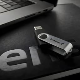 Intenso Office Line 256GB preto, vista lifestyle: pen drive com corpo preto e clip prateado sobre secretária junto a portátil