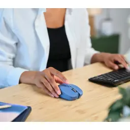 Trust Mydo Silent bleu, utilisation bureau: main tenant la souris sur bureau en bois avec clavier en arrière-plan