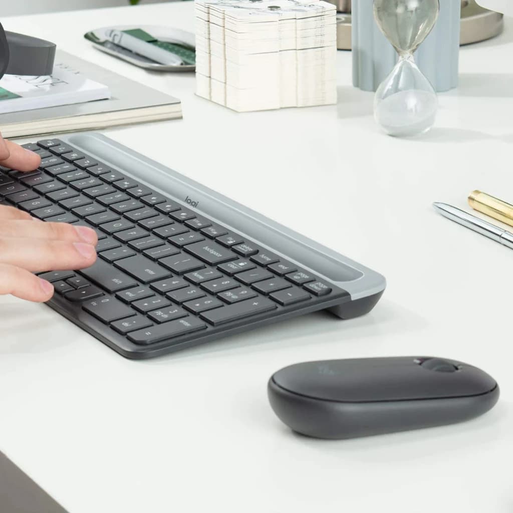 Logitech MK470 Slim Combo grafite, uso em secretária: mãos a digitar no teclado slim com rato sem fios ao lado