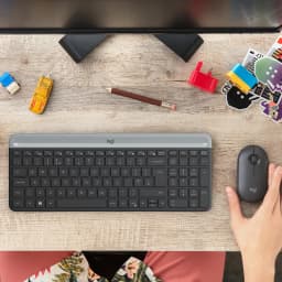 Logitech MK470 Slim Combo grafite, vista superior: teclado e rato sobre mesa de madeira com mão a usar o rato