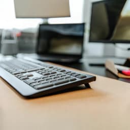 Cherry Teclado KW 3000 Inalámbrico QWERTY Negro, vista lateral: sobre escritorio con monitor desenfocado al fondo