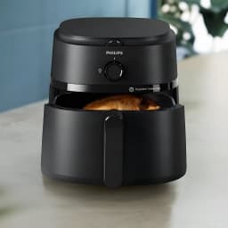 Philips Airfryer Serie 1000 NA130/00 6,2 l negro, vista frontal en cocina: cesta abierta con pollo asado dorado